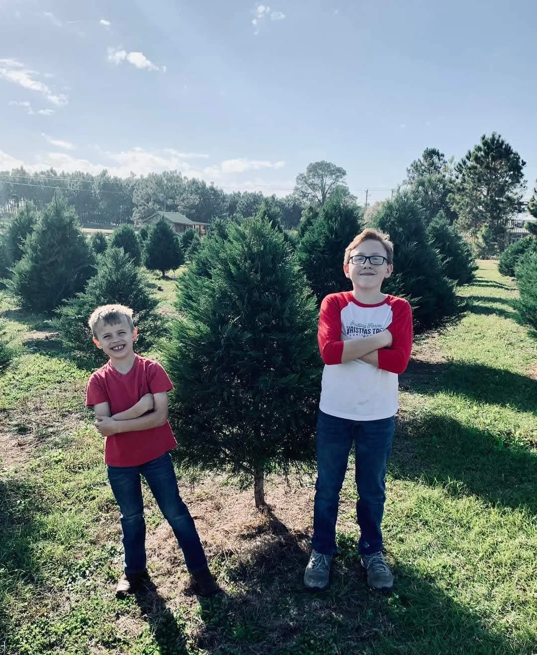 Two children standing beside a Christmas tree in the fields at Rutland Farms.
