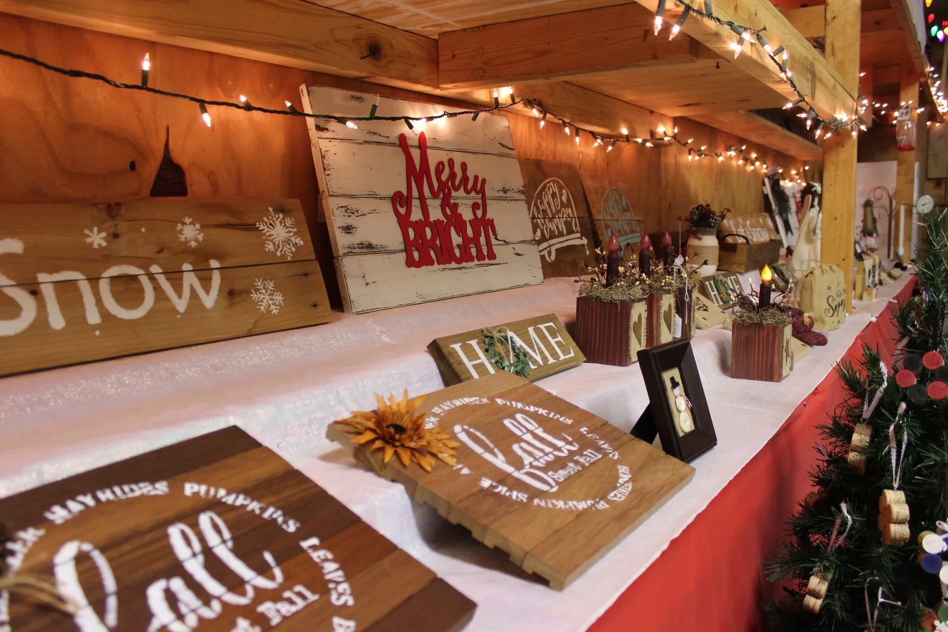Handmade holiday signs and decorations displayed under string lights in Gubser Tree Farm’s craft barn.