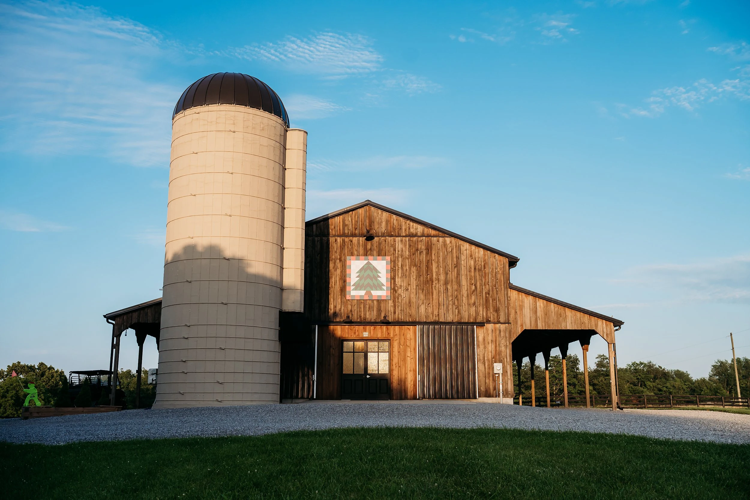 The wooden barn and tall silo at Sherwood Acres beneath a blue sky.