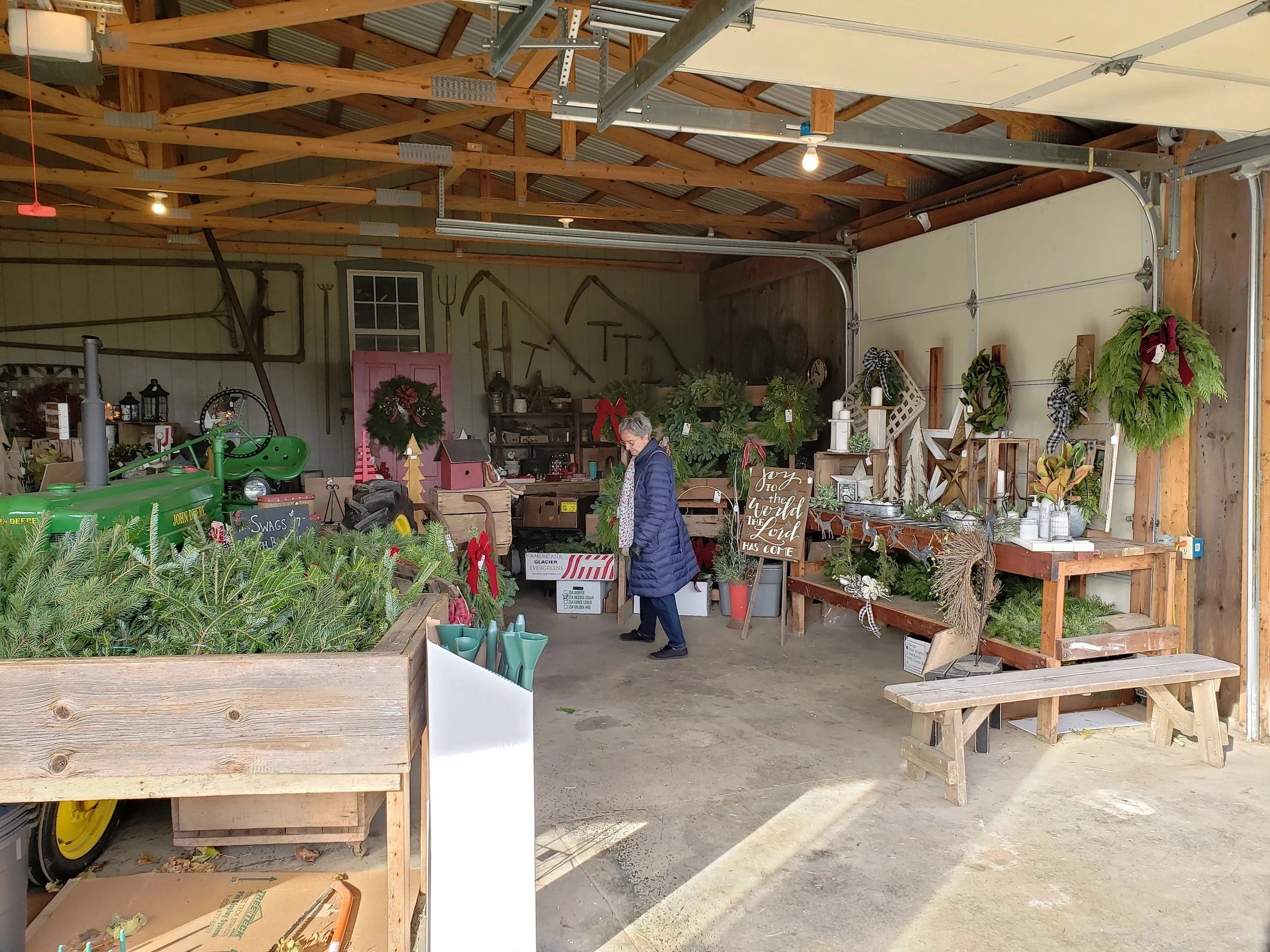 Wreaths, greenery, Christmas crafts and a green tractor inside the Wagner farm’s barn shop.